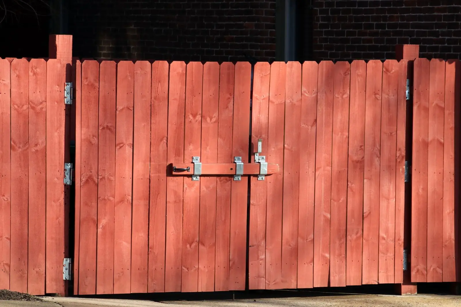 Red stained wood double gate with steel hinges and a slide latch